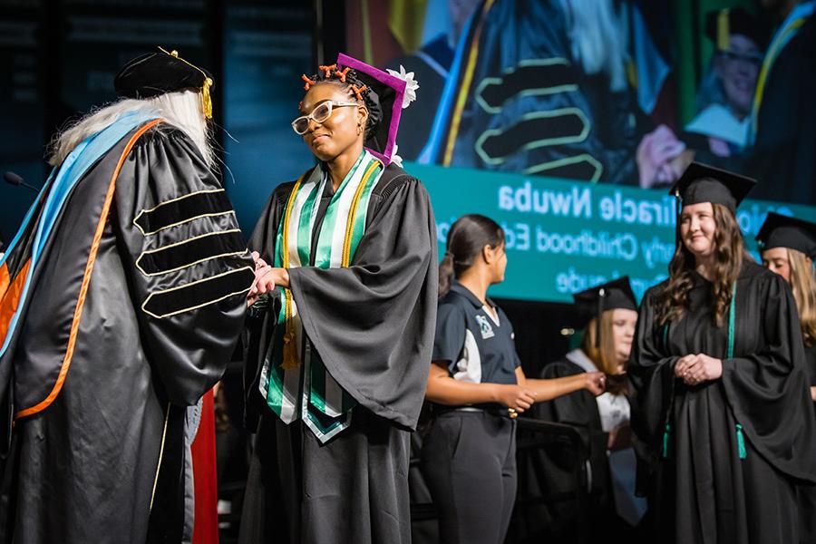 Obioma Nwuba, who graduated with a bachelor's degree in early childhood education, shakes the hand of Northwest Provost Dr. Jamie Hooyman during the University's commencement ceremonies. (Photo by Todd Weddle/Northwest Missouri State University)